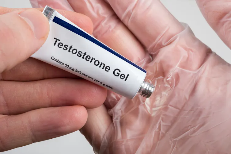 A man squeezing testosterone gel onto a glove hand before applying it.