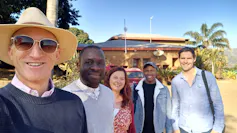 A group of five people standing outside smiling