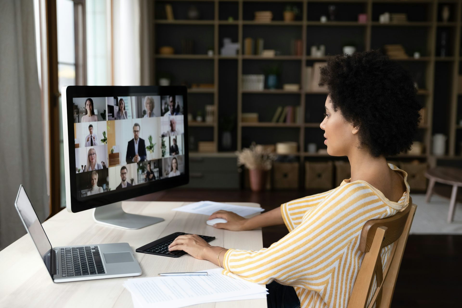 Una mujer teletrabajando asiste a una reunión virtual de su empresa en su pantalla desde casa