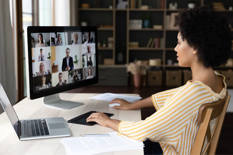 Una mujer teletrabajando asiste a una reunión virtual de su empresa en su pantalla desde casa