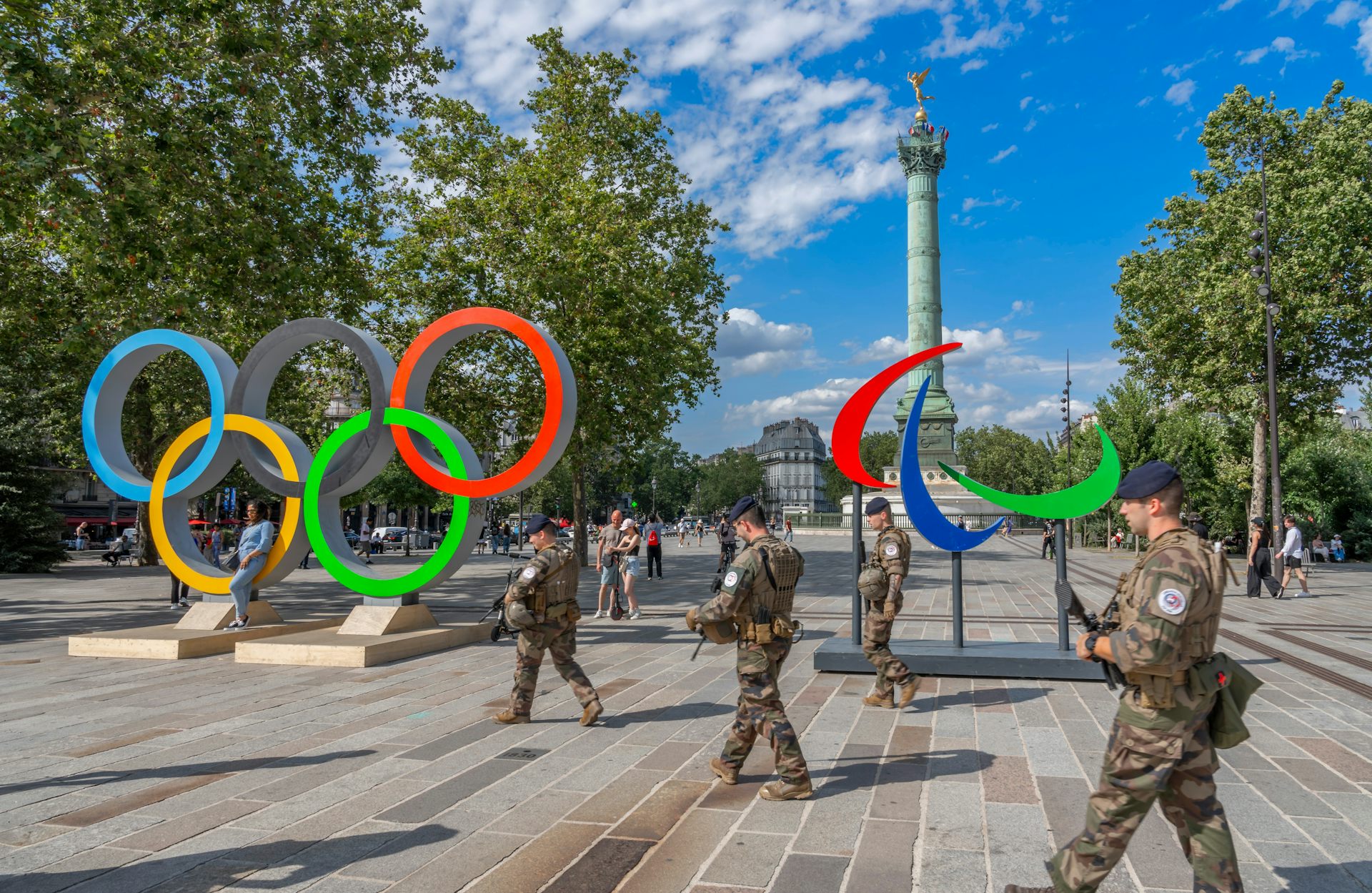 Vue de la place de la Bastille avec la colonne de juillet, les flammes paralympiques, les anneaux olympiques et les soldats avec armes marchent