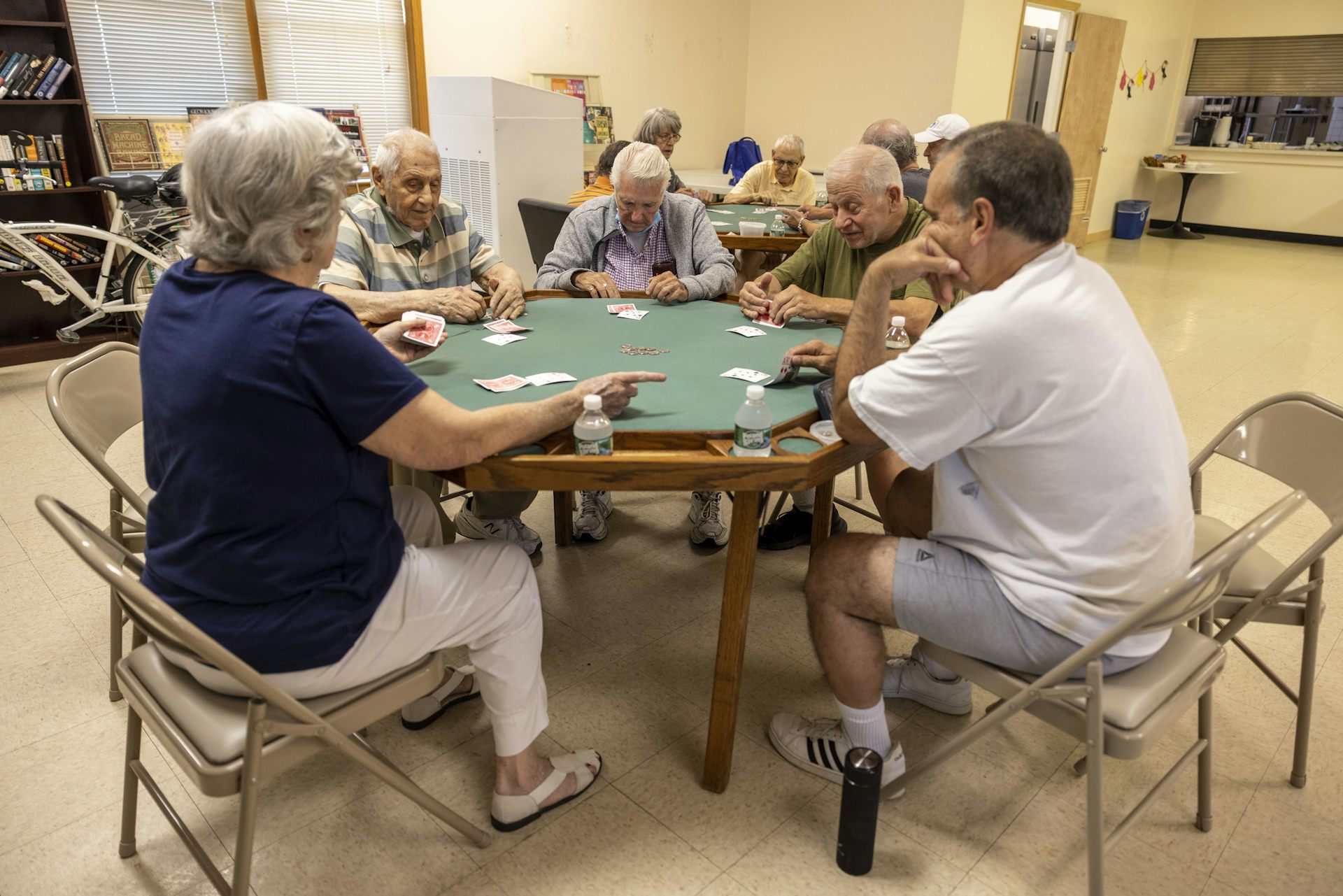 Un grupo de personas están sentadas alrededor de una mesa y jugando a las cartas.