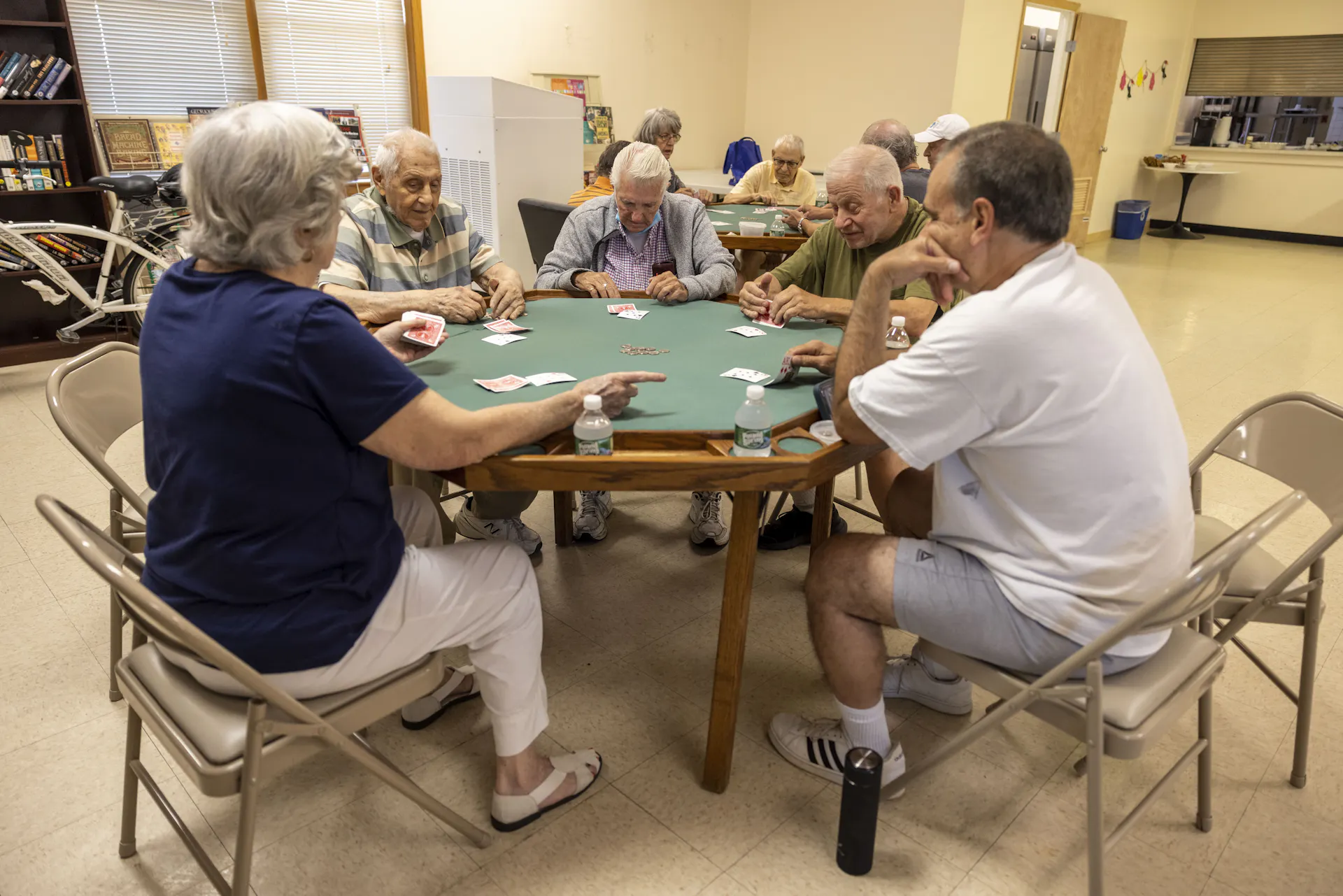 A group of people sit around a table and play cards.