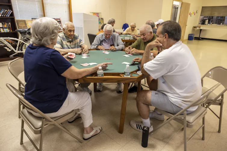 Por qué 78 grados no es la configuración adecuada del termostato para todos durante una ola de calor 2 Un grupo de personas están sentadas alrededor de una mesa y jugando a las cartas.
