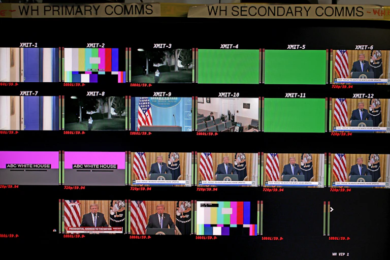 More than a dozen screens – labeled primary and secondary comms – show different views at and around the White House. A few show President Donald Trump behind a lectern.