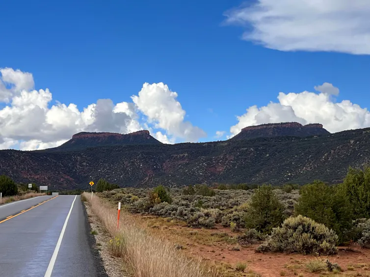 Twin rock formations reaching into a blue sky dotted with white clouds.