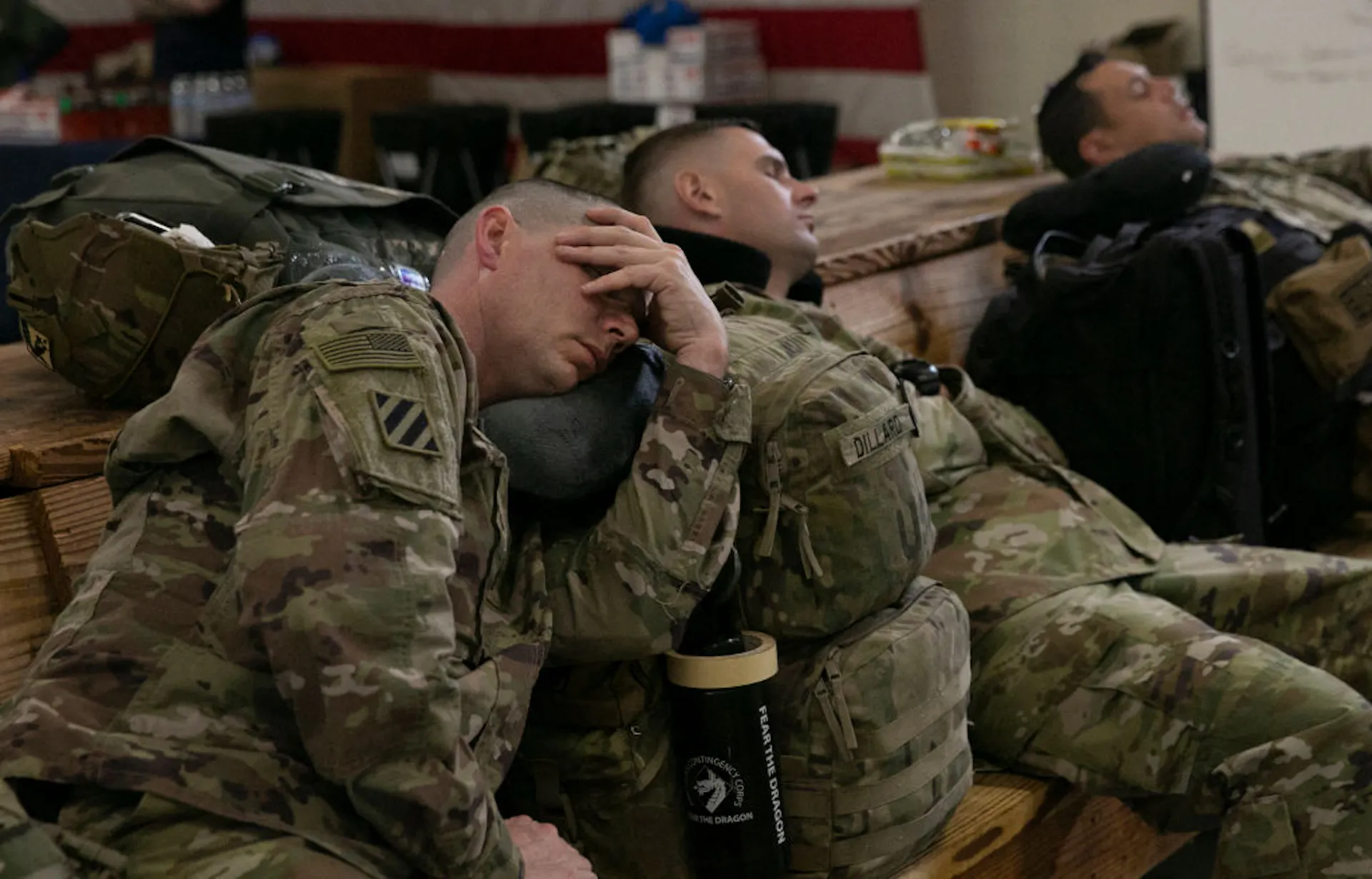 Three soldiers in uniform leaning back against a bench, asleep