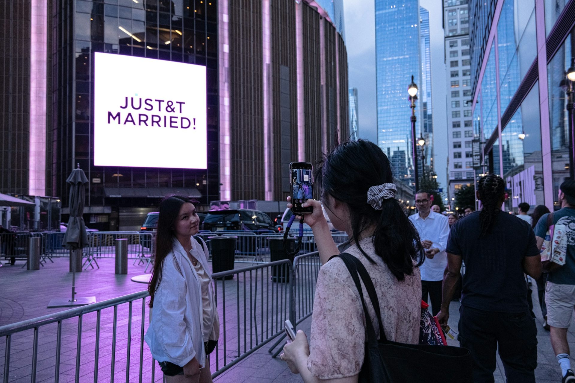Selfie being taken in front of city neon sign which reads 'JUST&T MARRIED!'