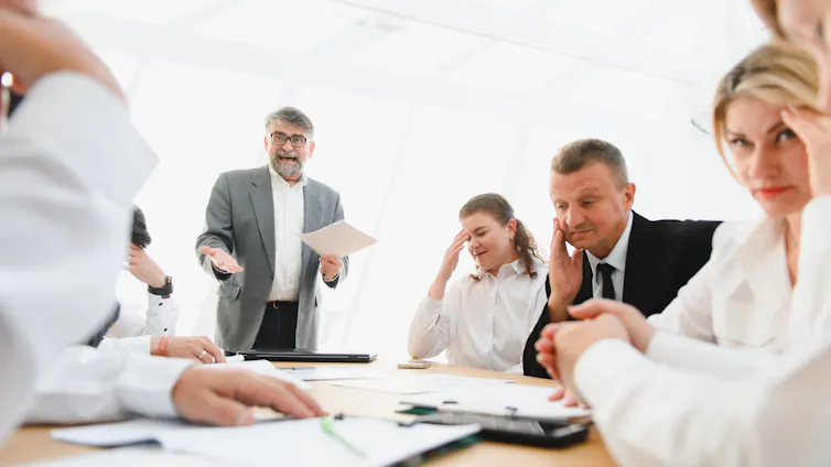 People looking uncomfortable around an office table.