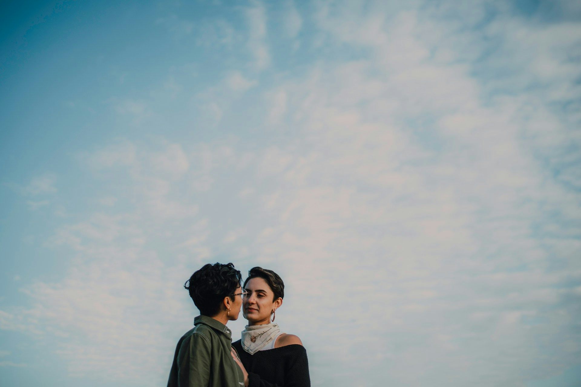 Two women, intimately close, against a large sky.