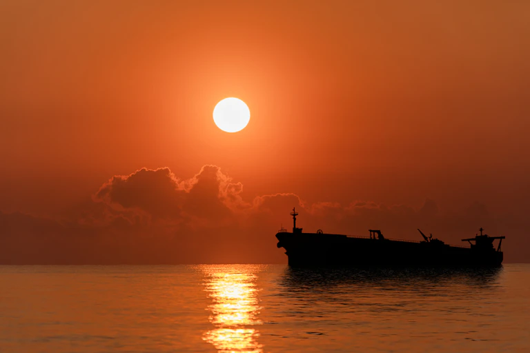 An oil tanker seen on the sea at sunset.