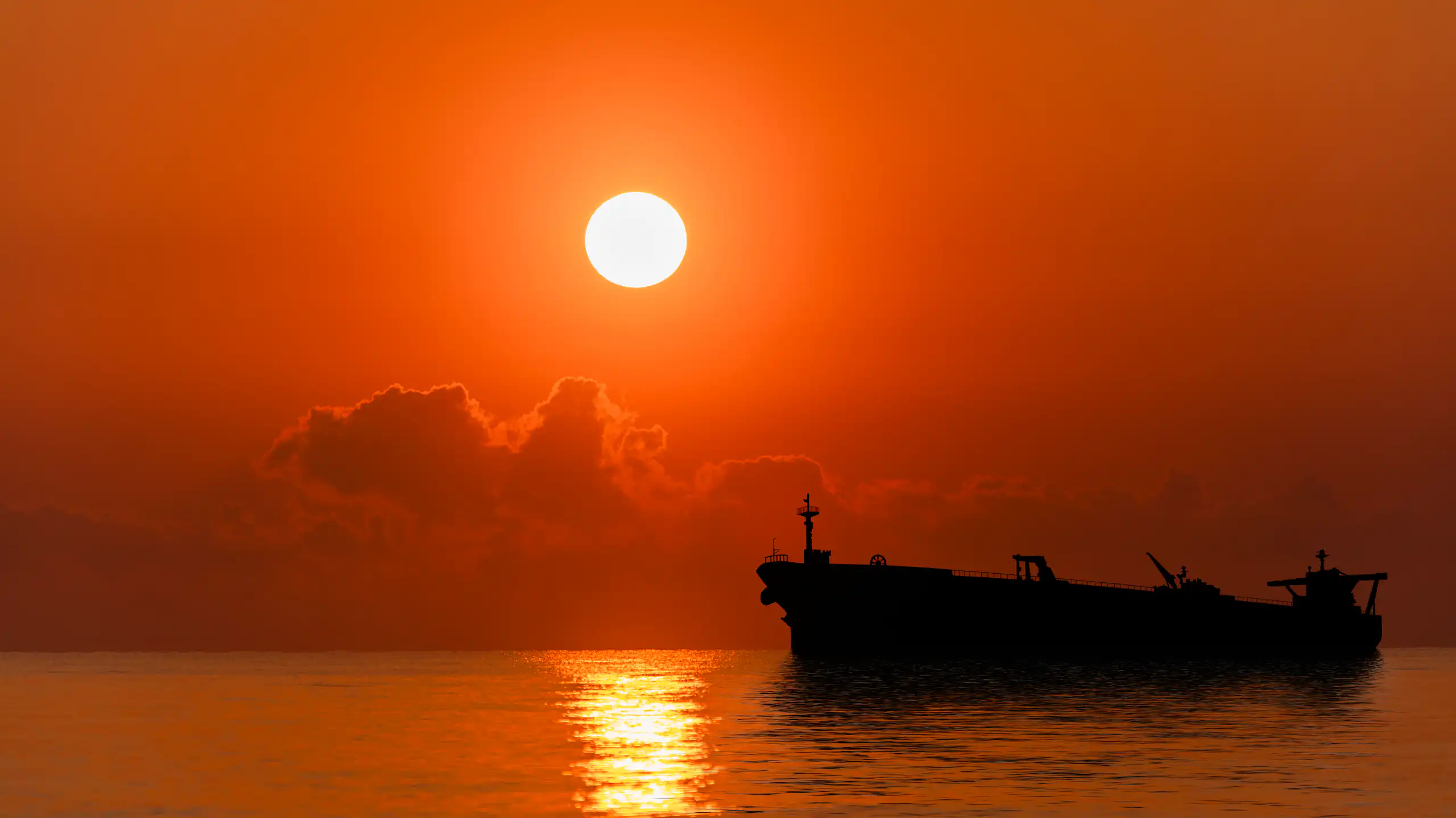 An oil tanker seen on the sea at sunset.