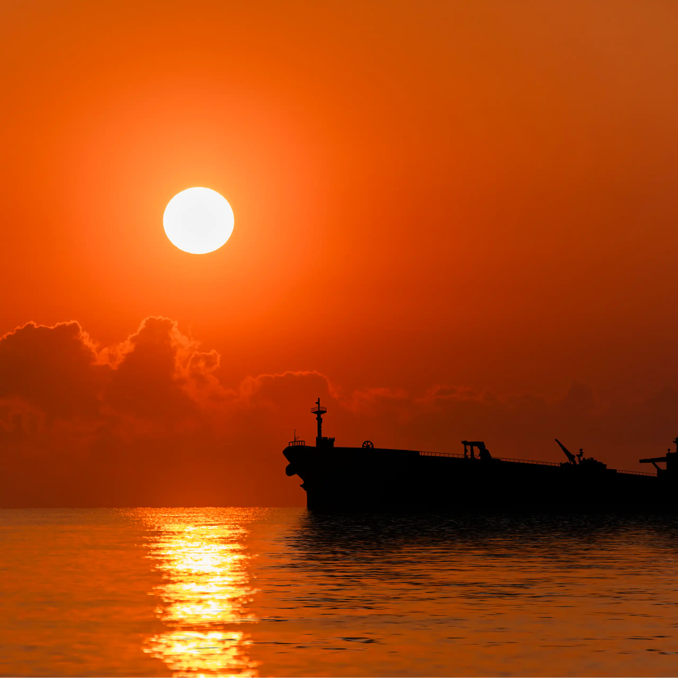 An oil tanker seen on the sea at sunset.