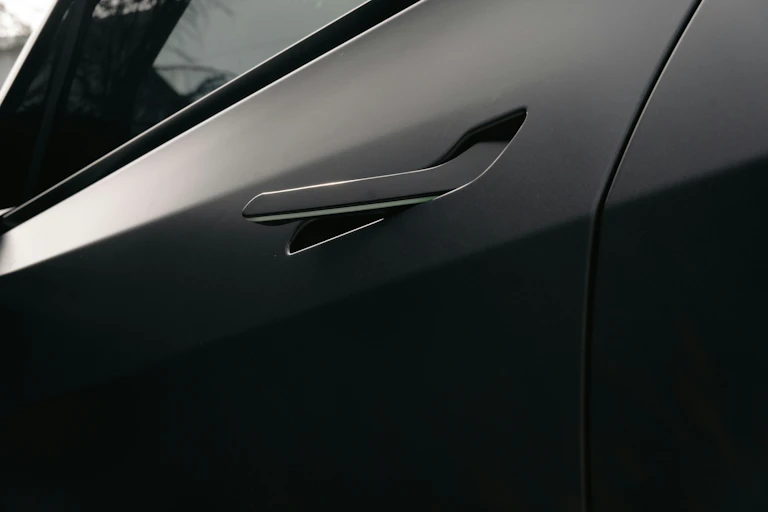A close up of a black electric car with a flush car door handle