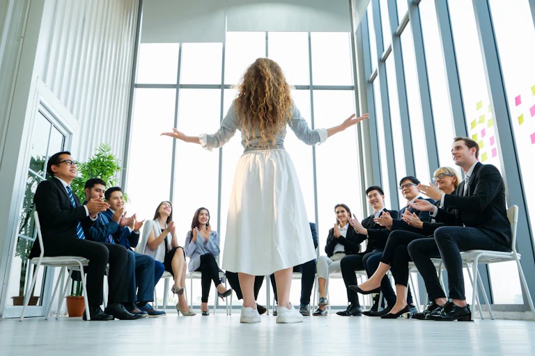 Manageuse devant des collaborateurs assis.