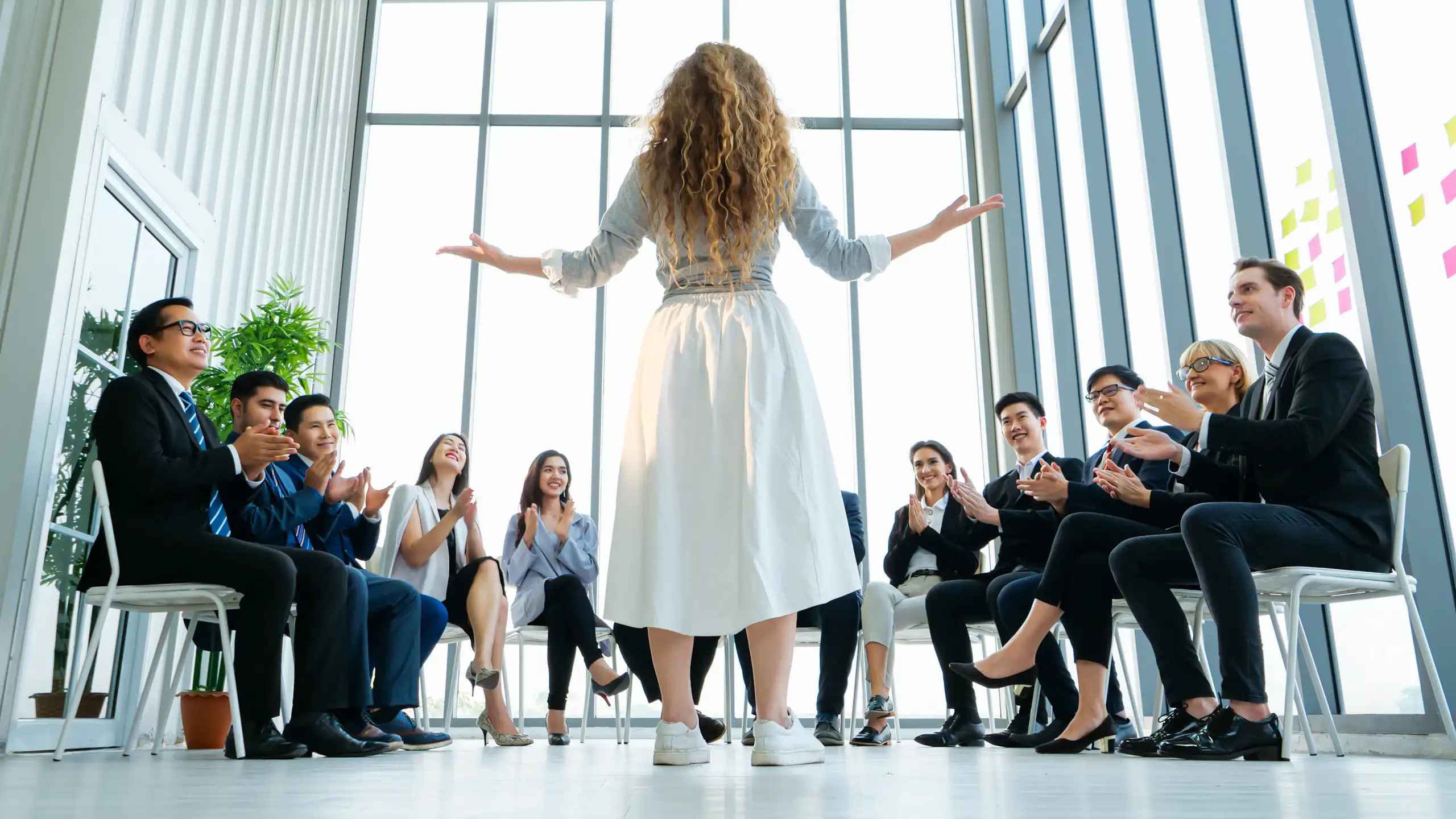 Manageuse devant des collaborateurs assis.
