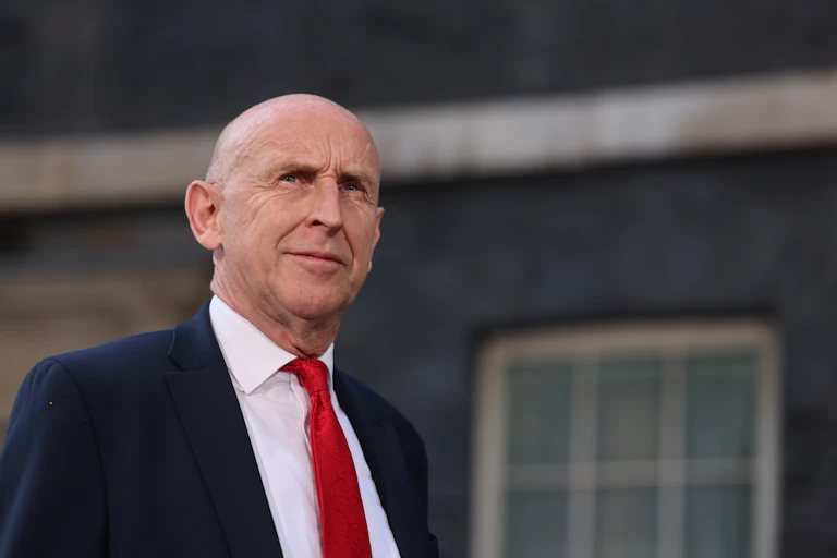 john healey outside 10 downing street in navy suit and red tie.