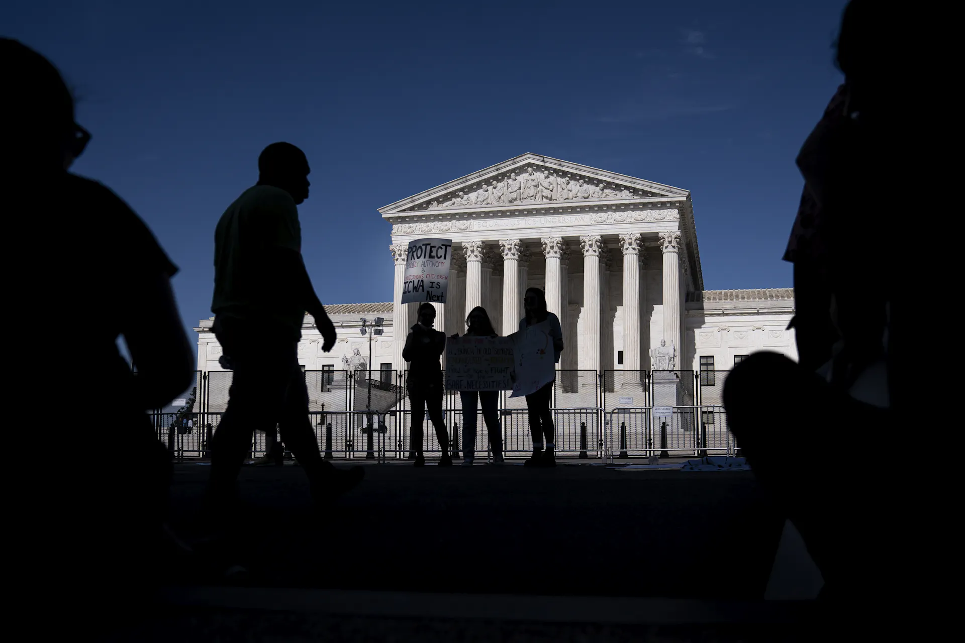 Several people gather in front of a federal building with columns.