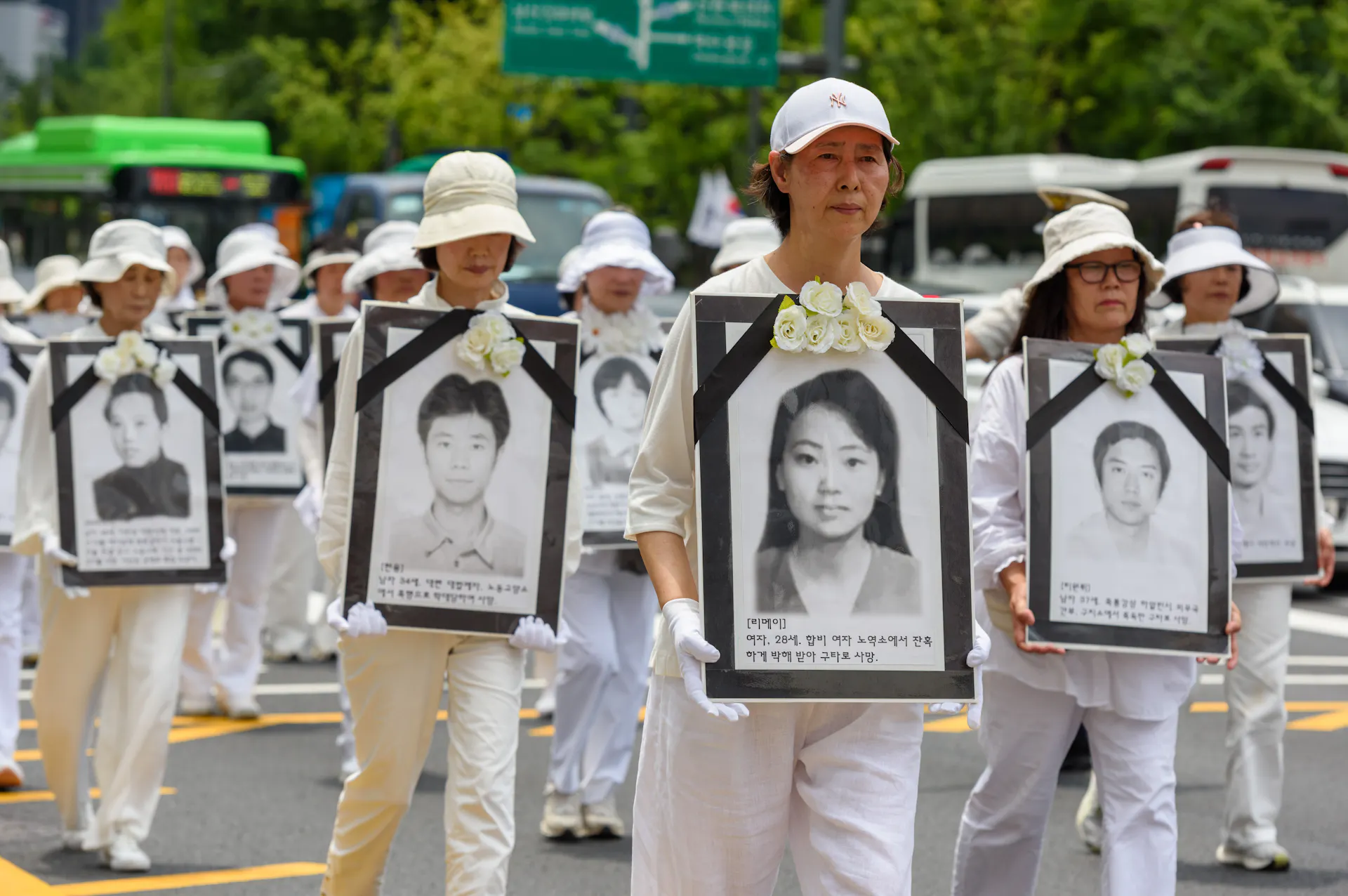 Protesters wearing white caps hold photographs of people during a demonstration.