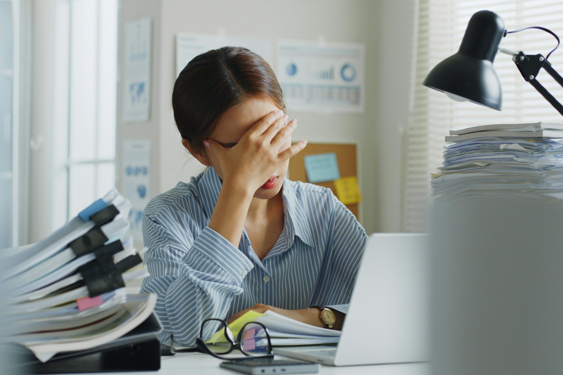 Une femme assise à son bureau est désespérée devant une montagne de documents