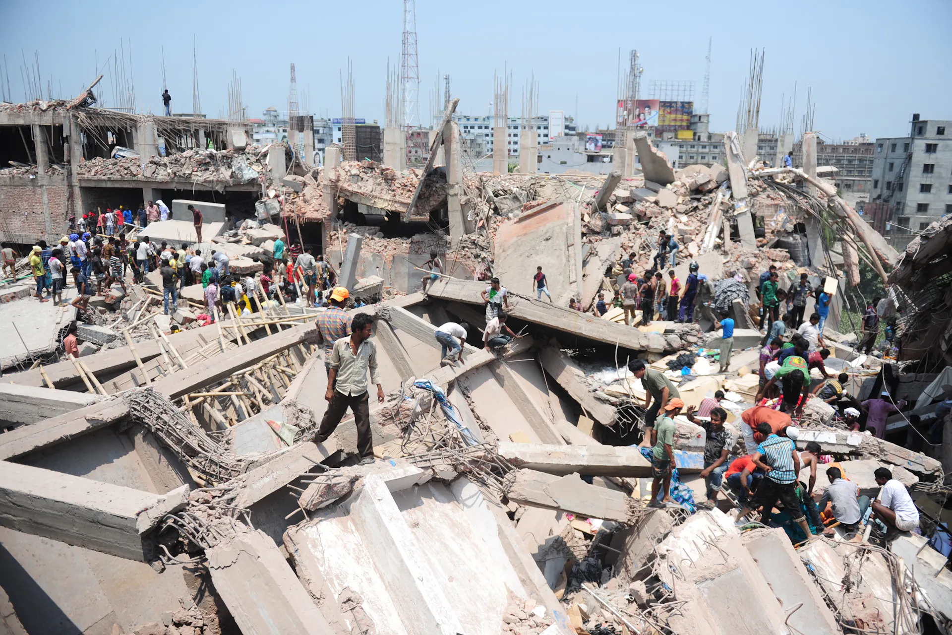 People scramble across piles of concrete and metal rubble.