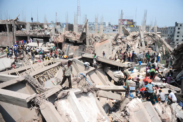People scramble across piles of concrete and metal rubble.
