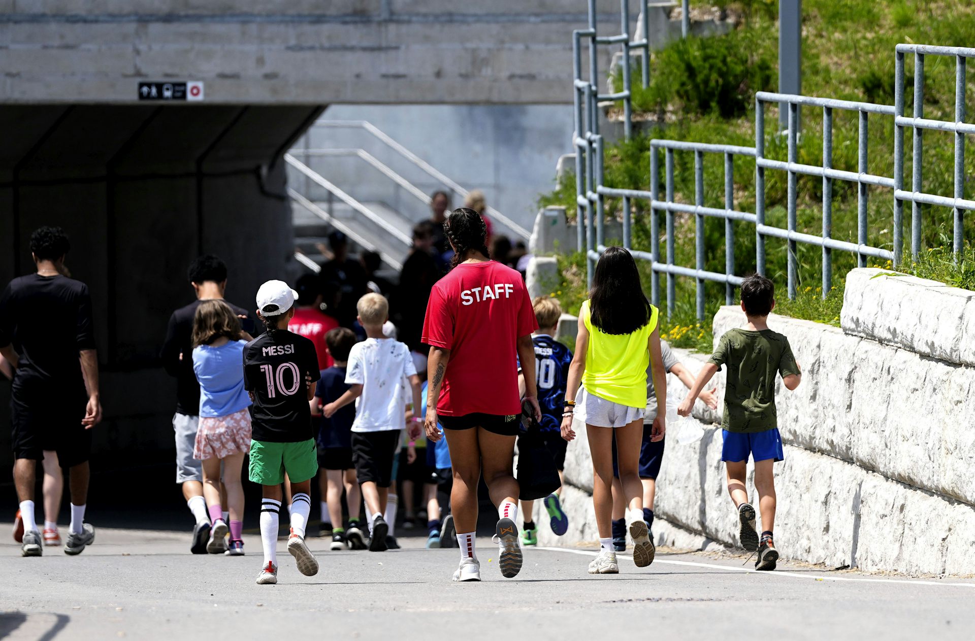 Children seen walking with a person in a shirt that says 'staff.'
