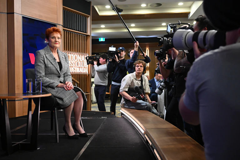 Pauline Hanson surrounded by cameras and reporters.