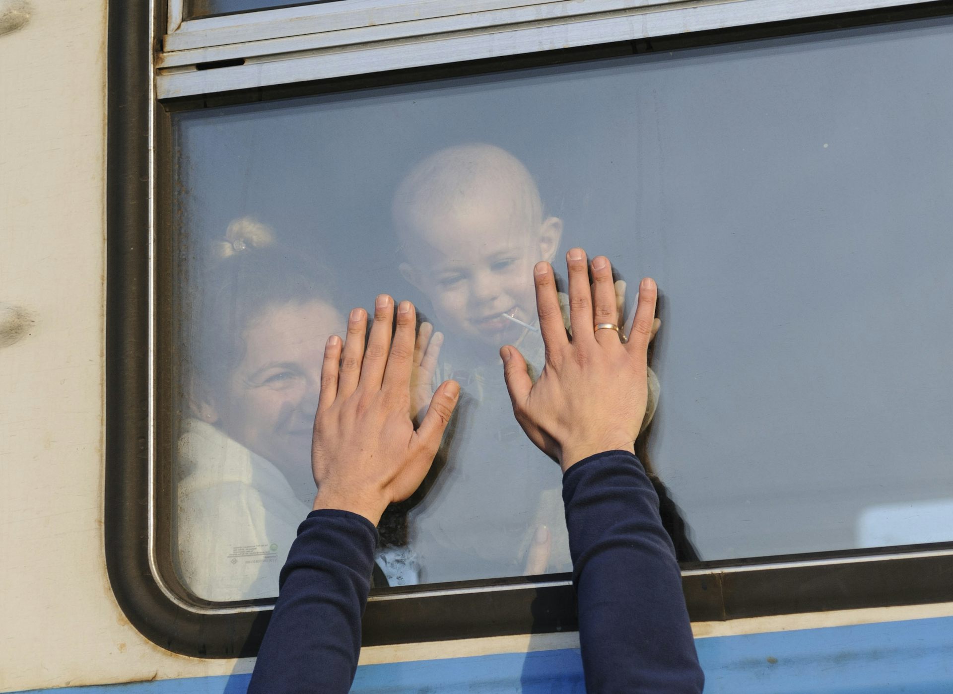 Los refugiados ucranianos se despiden con la mano mientras se marchan en tren.
