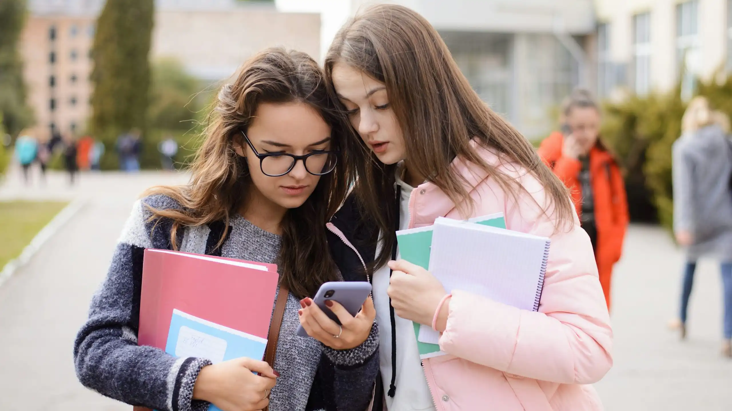 Dos chicas observan la pantalla de un móvil.