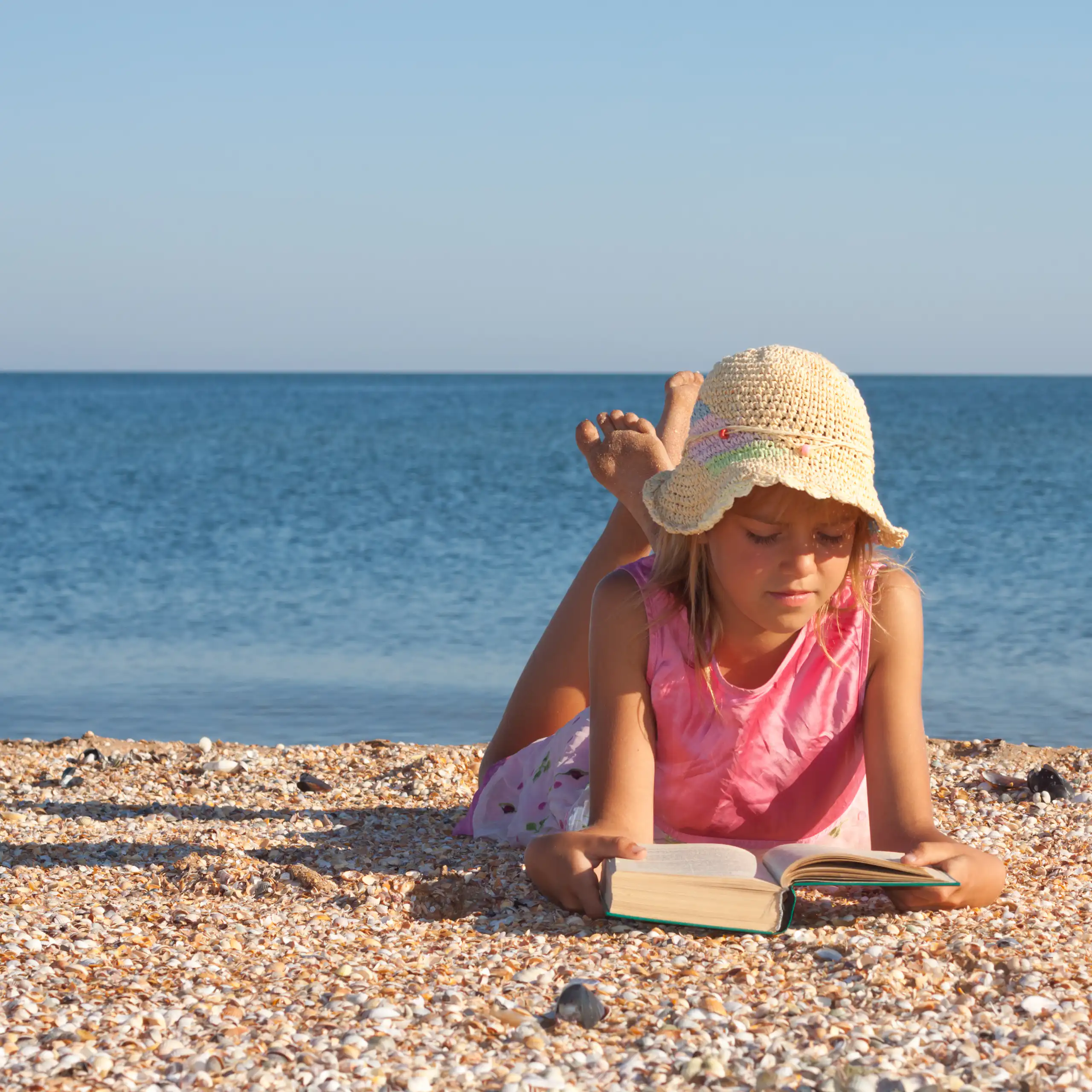 Una niña leyendo en la playa