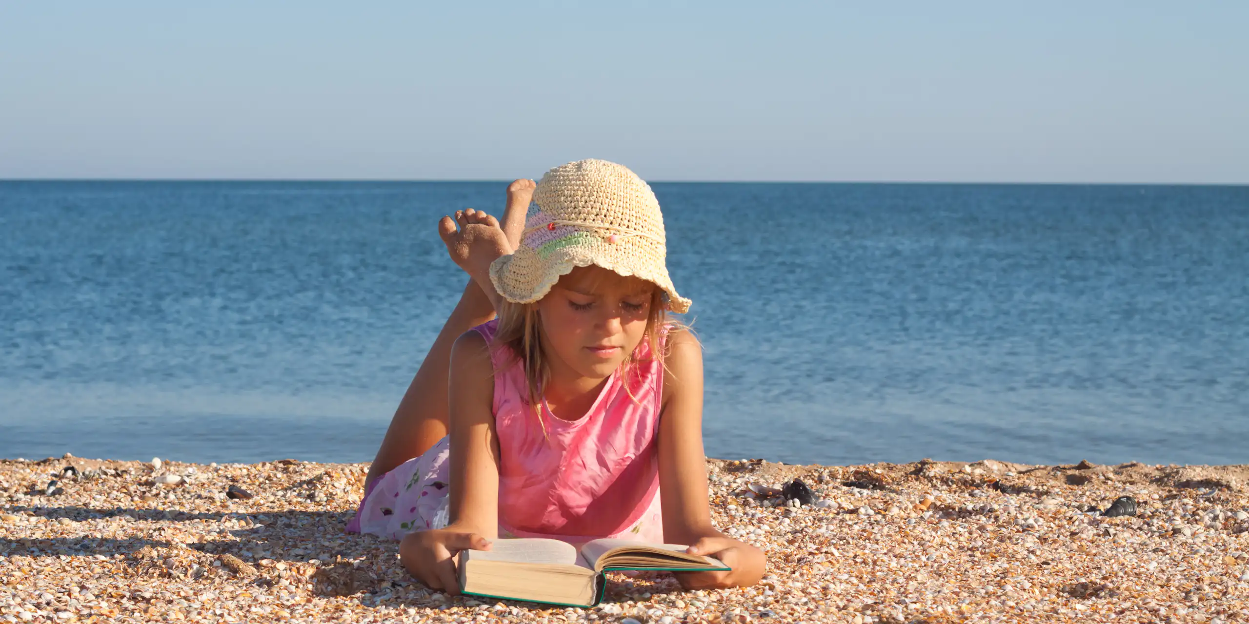 Una niña leyendo en la playa