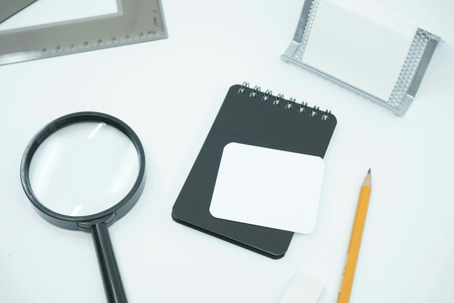 A magnifying glass next to a computer and notepad.
