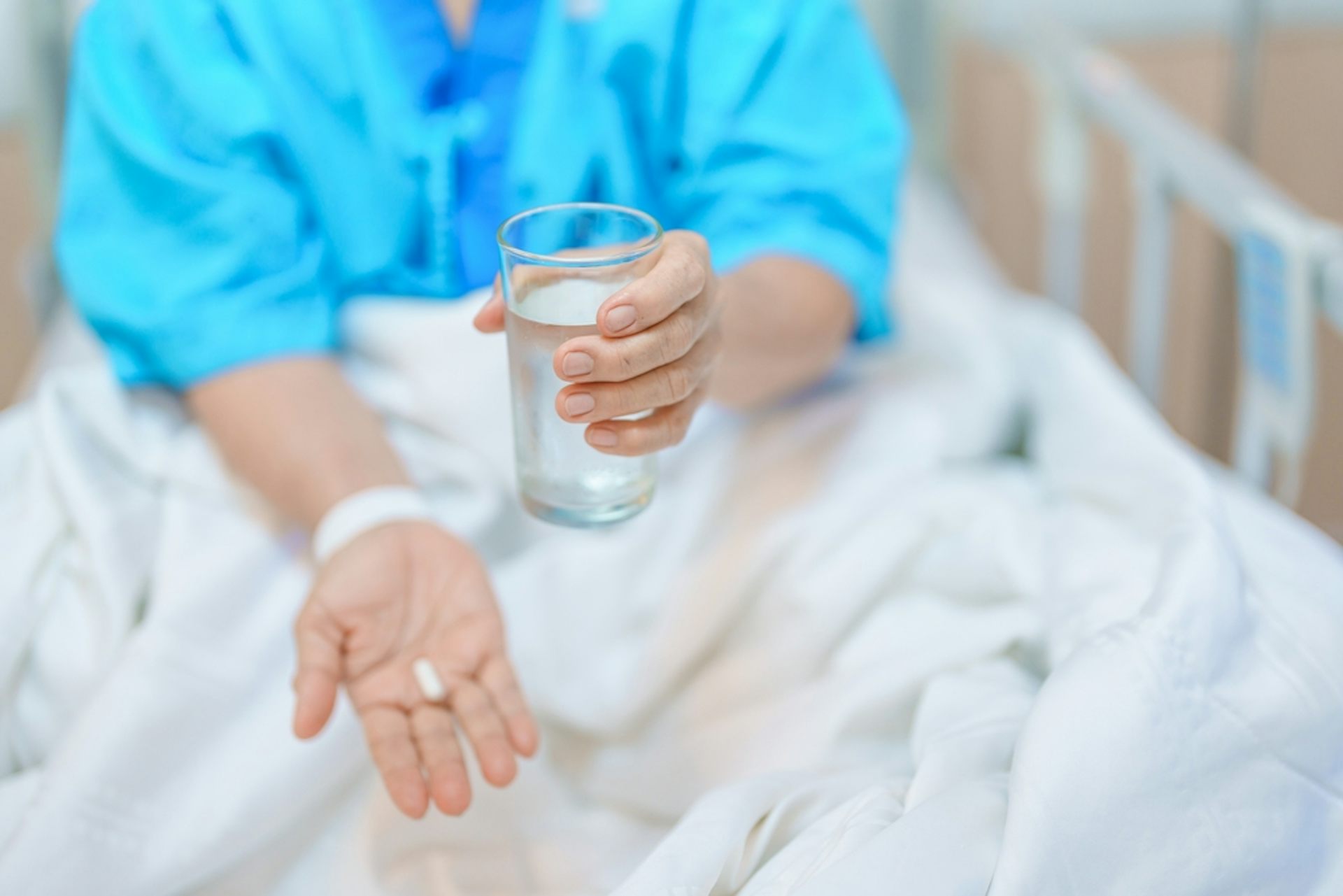 A patient in a hospital bed about to take a pill.