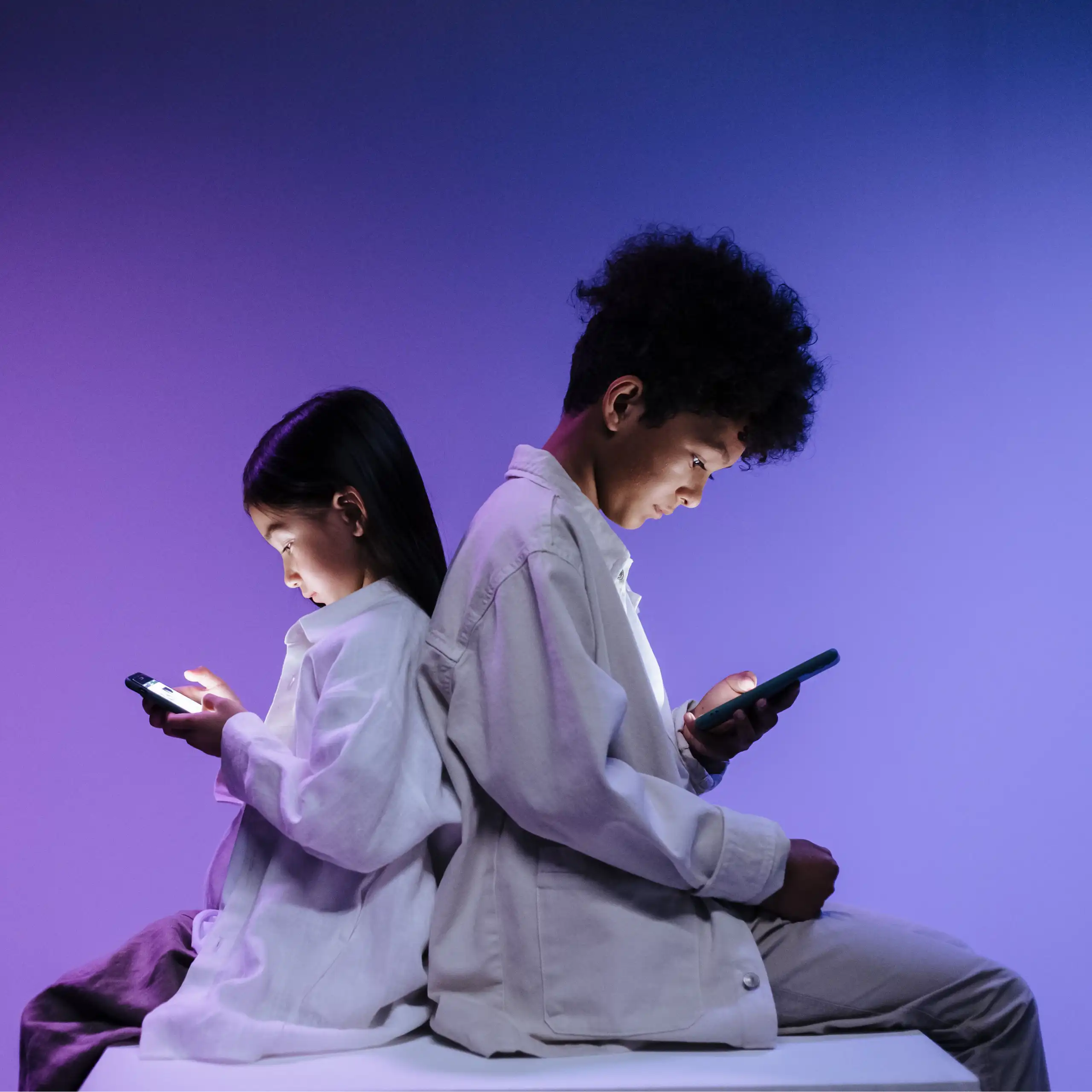 Two children back to back using smartphones on a vibrant purple background.