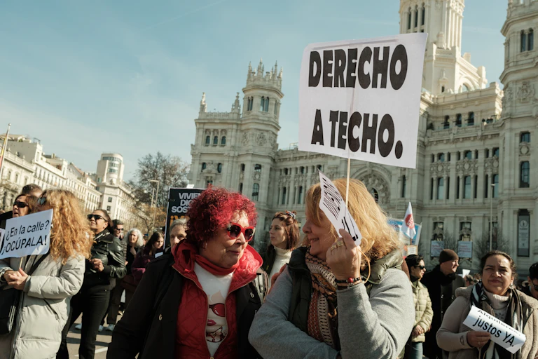 Mujeres en una manifestación. Una de ellas lleva una pancarta donde puede leerse "derecho a techo".