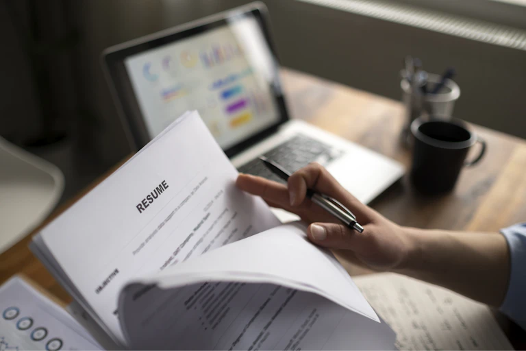 Person examining resumes and job applications at a desk