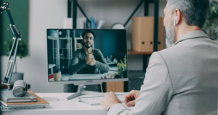 Man interviews another man online via video call on a desktop computer