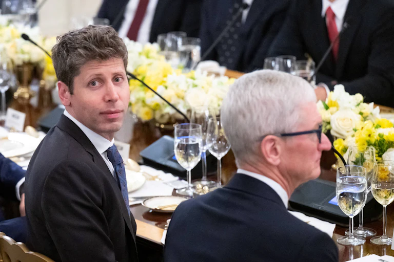 OpenAI CEO Sam Altman and Apple CEO Tim Cook sitting next to each other at a table