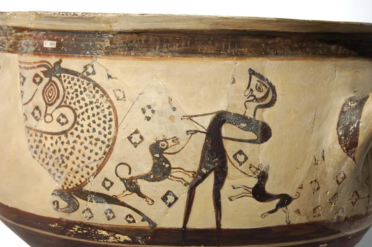 On one side of the bowl is a scene of man on left restraining a dog (?) on a leash with each hand, to the left is a bull, painted in outline filled with spots, facing towards the right but with its head turned to the left.