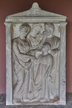 Grave monument for a young girl named Euchalia, depicting her with her parents, grandmother and a small dog poised on its hind legs and pawing at her knees