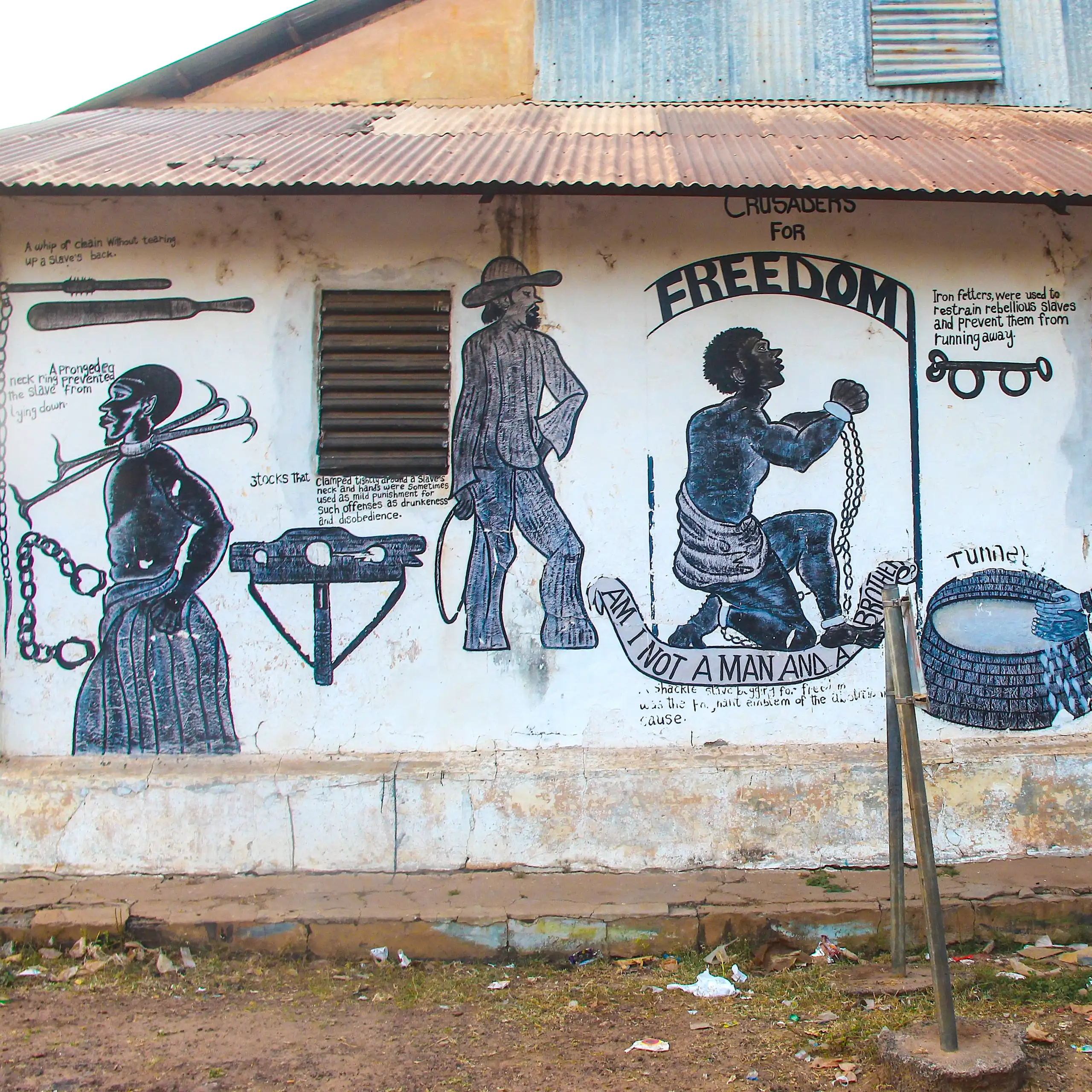 A mural shows depictions of enslaved people in shackles and colonial masters in western clothing.