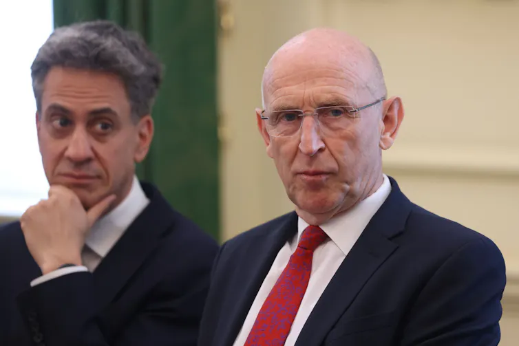 ed miliband eyes john healey suspiciously in the first cabinet meeting of andy burham's premiership.
