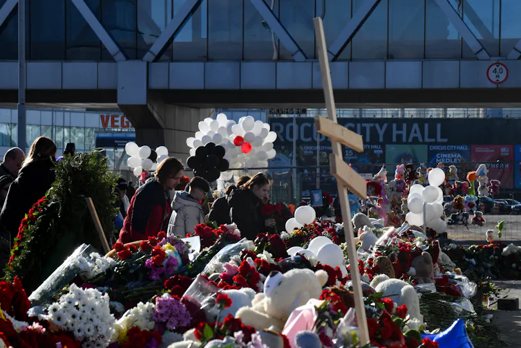 Flowers, balloons and teddy bears are scattered around a makeshift memorial