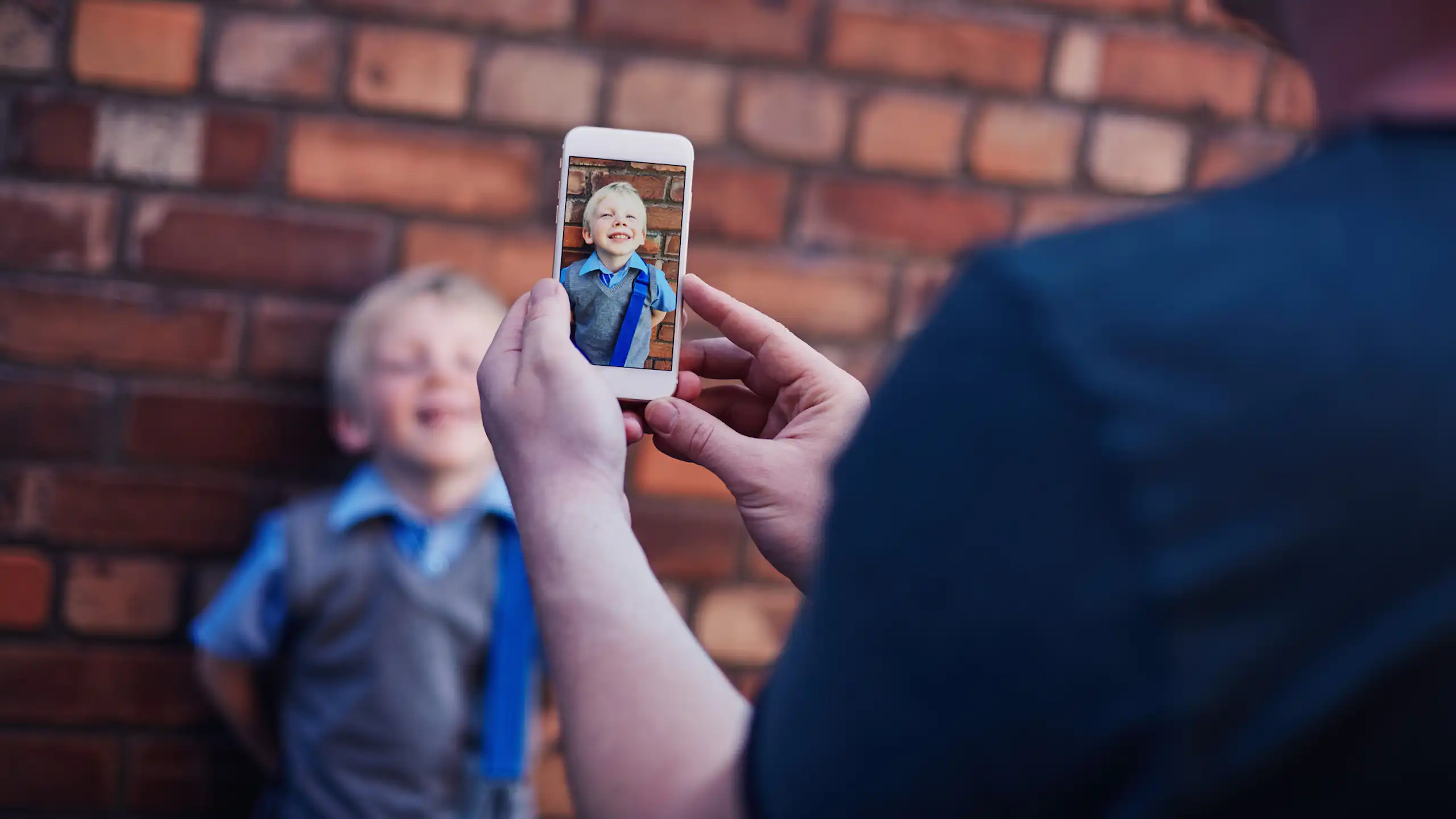 An adult takes a photo on a phone of a young child.