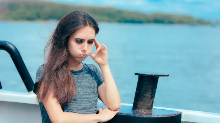 Mujer con gesto de mareo en la cubierta de un barco