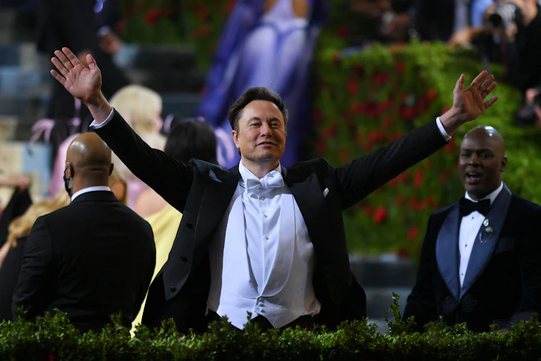 A man in evening dress holding his arms aloft.