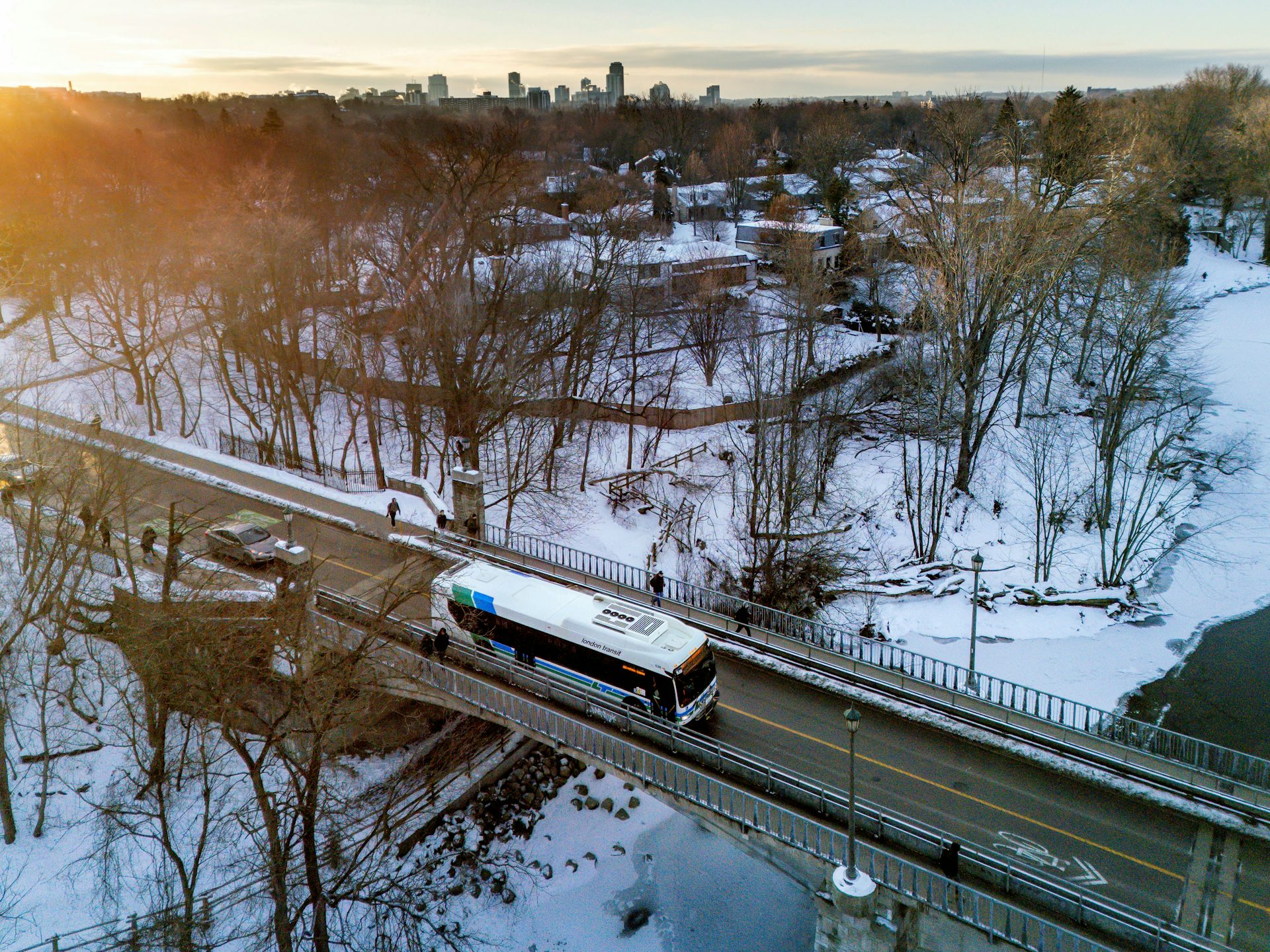 A bus travels along a bridge over a snowy ravine.