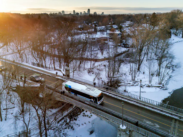 A bus travels along a bridge over a snowy ravine.