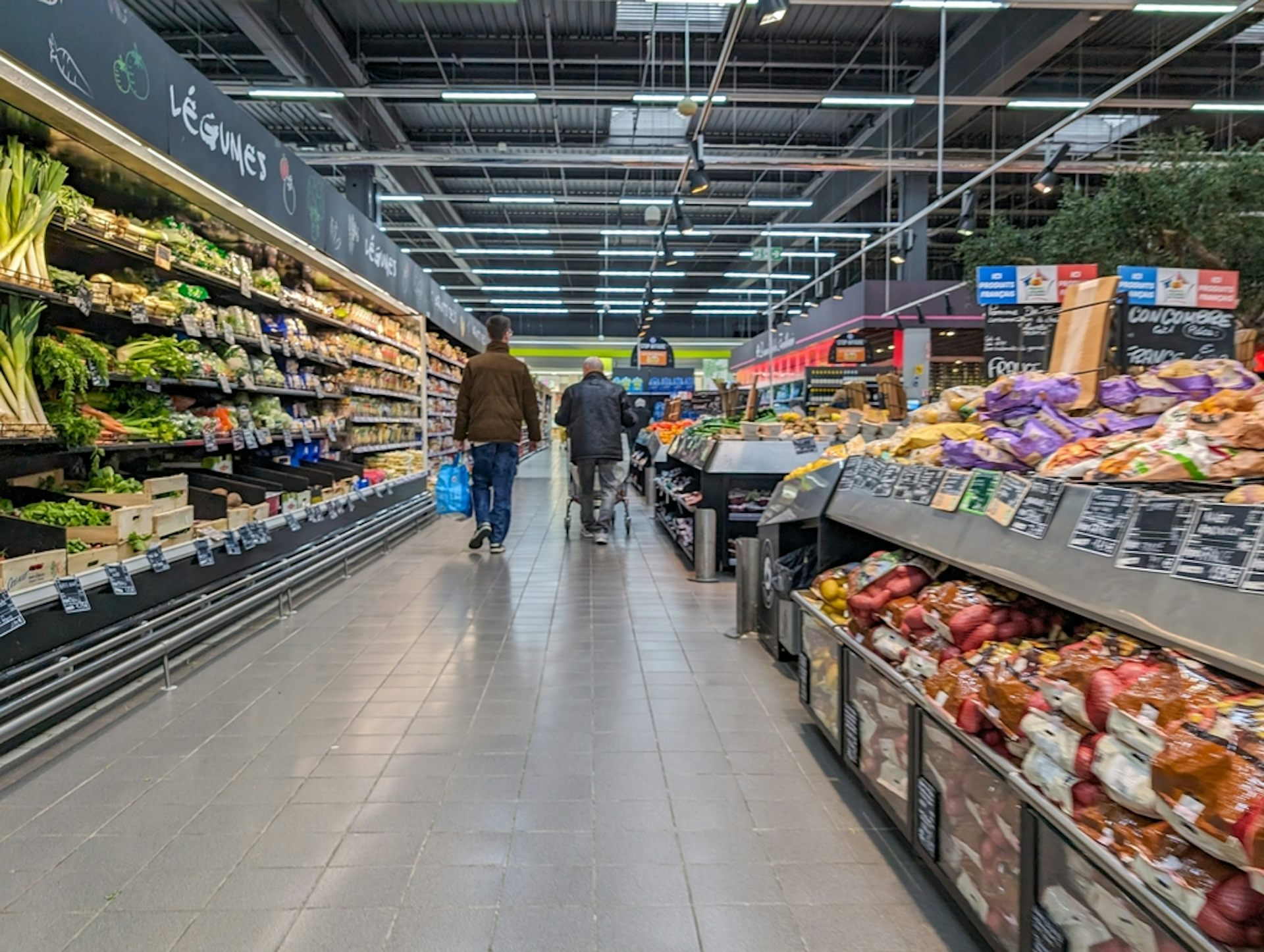 Deux personnes de dos dans l'allée d'un supermarché.